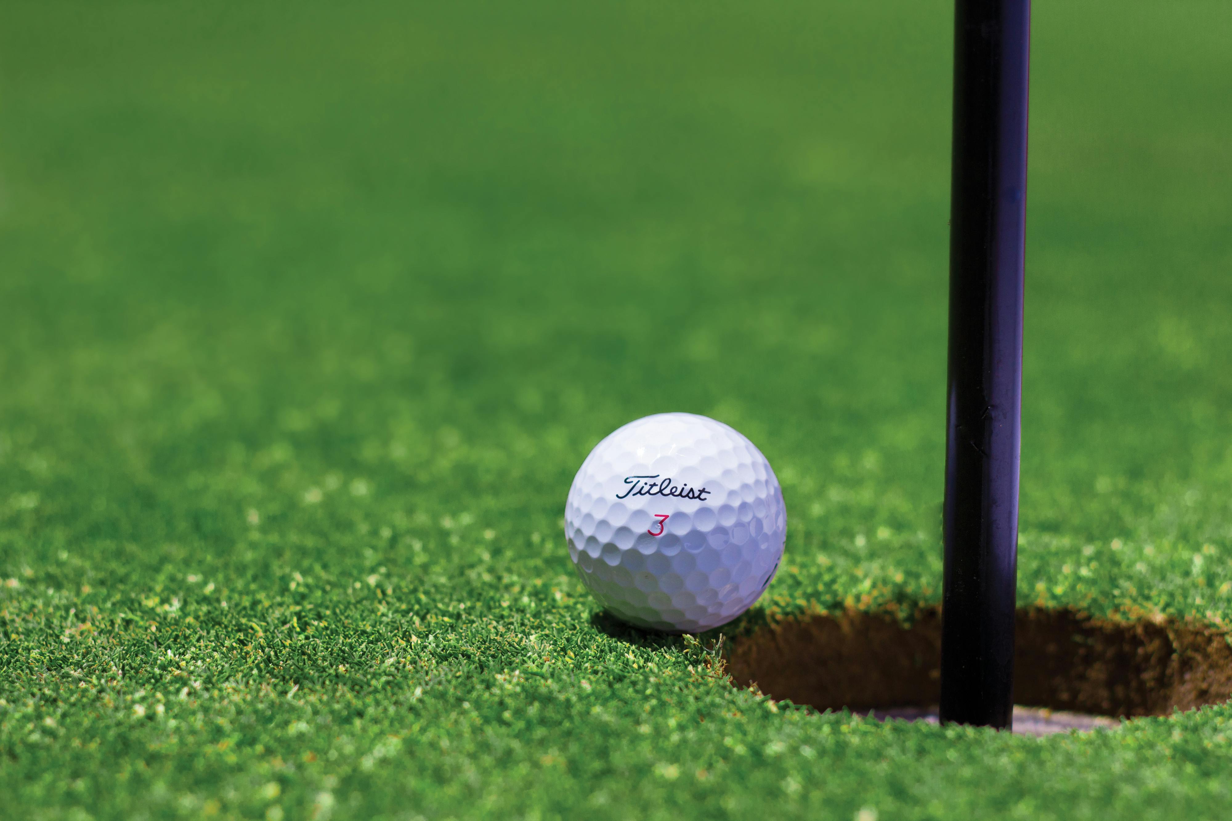 Image of golf ball on tee on grass.